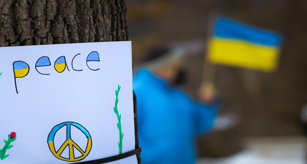 foglio con scritto peace, simbolo della pace nei colori della bandiera ucraina con bandiera ucraina sullo sfondo